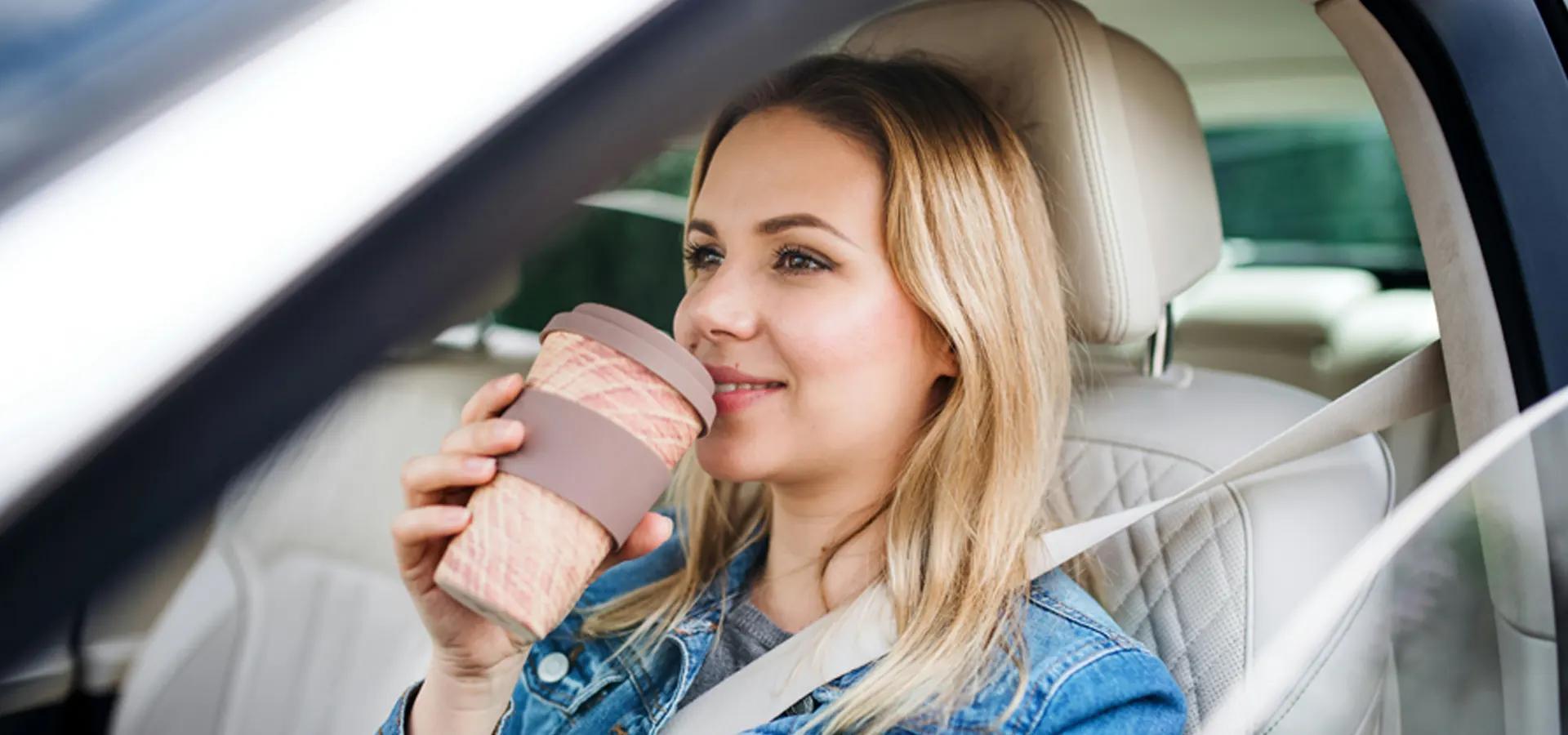 Woman sitting in car drinking coffee